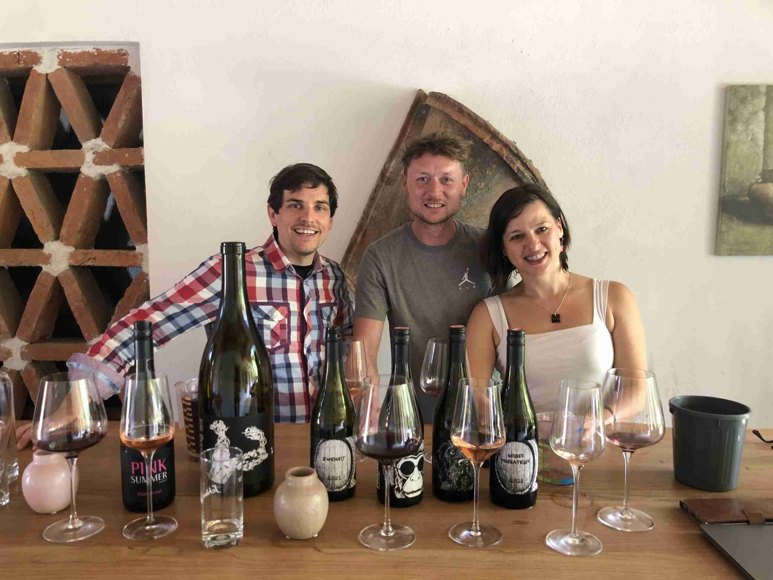 Joanne with two fellow tasters around a table of wine bottles and tasting glasses.
