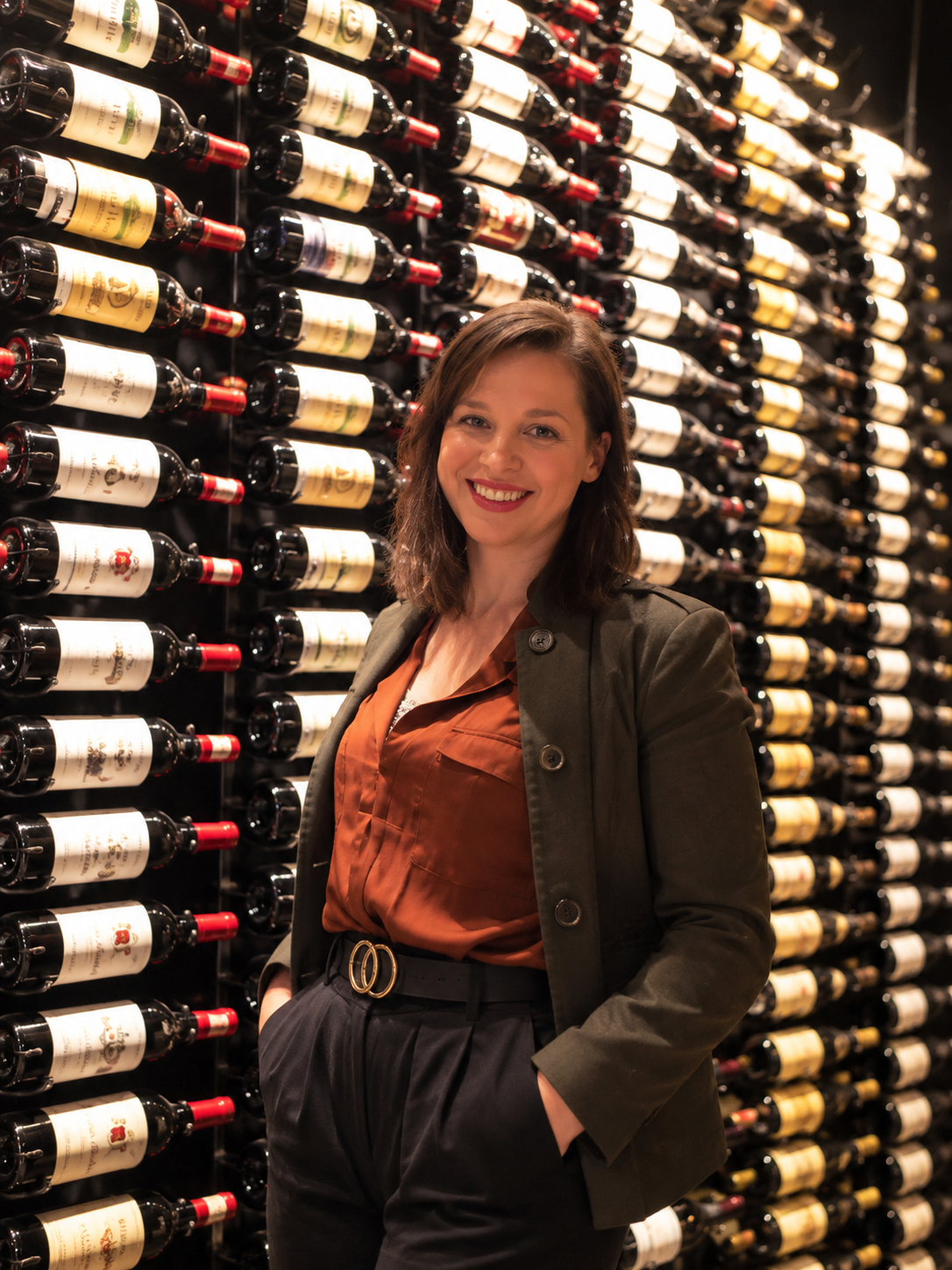 Joanne DiGeso of SommWine in front of a wall of wine bottles